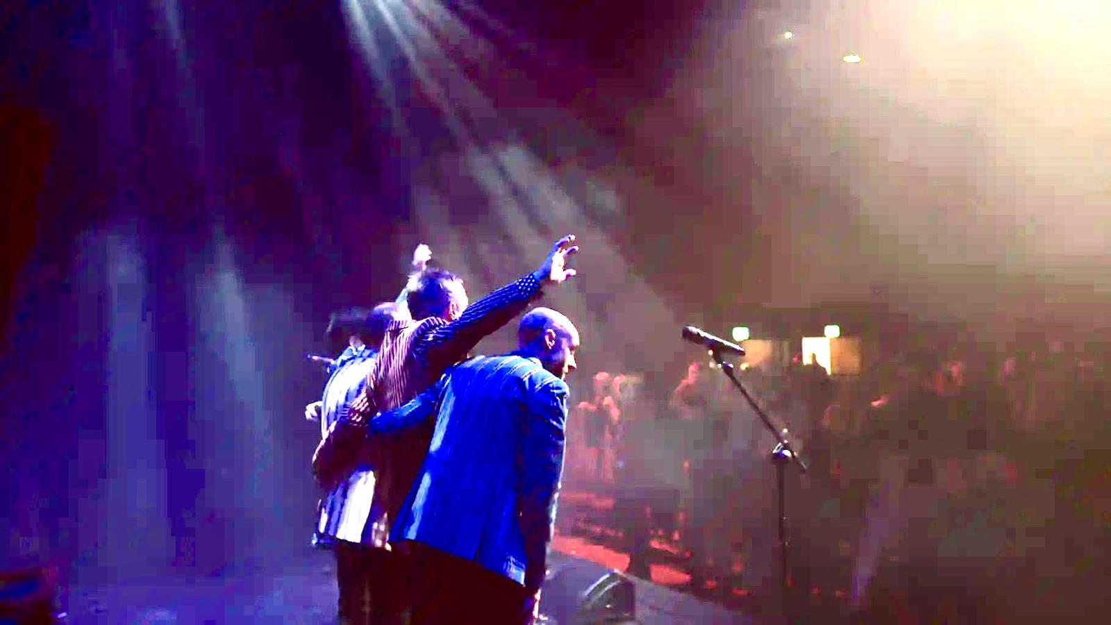 The band with arms around each other saluting the crowd at the end of the show